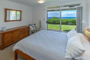Un dormitorio con una cama y una ventana con el mar. en Blue Pacific, en Blueys Beach