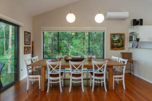 a dining room with a wooden table and chairs at A Yarraangunthi in Smiths Lake