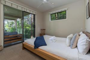 a bedroom with a large bed and a sliding glass door at A Yarraangunthi in Smiths Lake