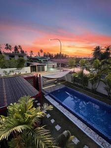 a swimming pool in front of a building with a sunset at M-Residence in Pantai Cenang