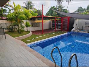 a swimming pool in front of a house at M-Residence in Pantai Cenang