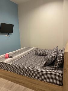 Schlafzimmer mit einem Bett mit Kissen und einem TV in der Unterkunft ศิริณเพลส อพาร์ตเมนต์ใกล้สถานีรถไฟ ใกล้วัดป่านานาชาติ อุบลราชธานี in Ubon Ratchathani