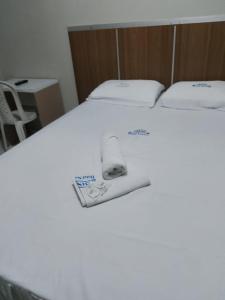 Una cama blanca con dos almohadas y un libro. en HOTEL NOVAES, en Castanhal