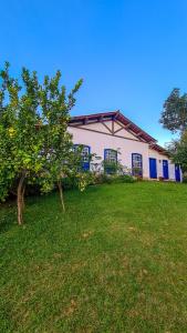 um edifício branco com uma árvore no quintal em Segredo da Serra Guest House em Tiradentes