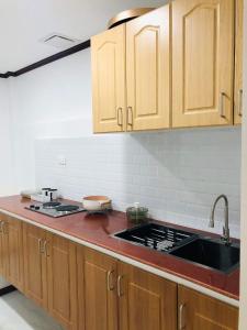 uma cozinha com armários de madeira e um lavatório em Jirah’s inn em Legazpi
