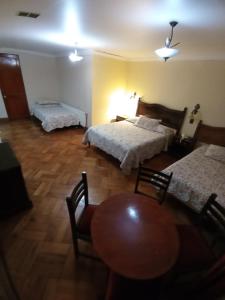 1 dormitorio con 2 camas, mesa y sillas en Hotel Paris Ltda., en Santiago