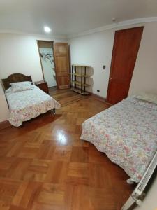 um quarto com 2 camas e piso em madeira em Hotel Paris Ltda. em Santiago