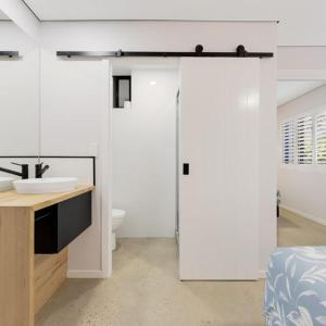 Baño blanco con aseo y lavamanos en Joanne Apartments, en Caloundra