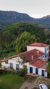 two white buildings with blue doors and a mountain at Segredo da Serra Guest House in Tiradentes