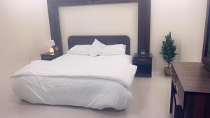 a bedroom with a bed with white sheets and pillows at شقه مفروشة فاخره بدخول ذاتي in Al Kharj