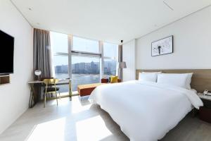 釜山にあるOcean 2 Heaven Hotelの大きなベッドと大きな窓が備わるホテルルームです。