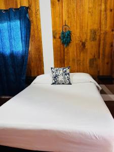 un letto bianco con un cuscino sopra di Blue House a Puerto Escondido