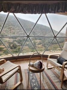 Albaha domes في Rahwat al Barr: غرفة مع نافذة كبيرة مع كراسي وطاولة