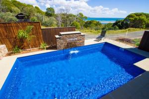 a blue swimming pool with a view of the ocean at Moorings - Beach house with pool in beautiful 1770 in Seventeen Seventy