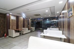 un restaurante con mesas y sillas blancas y paredes de madera en Collection O Hotel City Point en Gurgaon