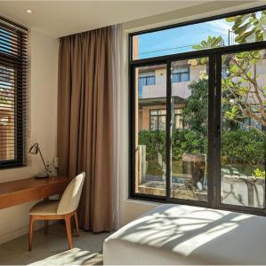 a bedroom with a bed and a desk and a large window at Big Star Villas - Wyndham Garden in Cam Ranh