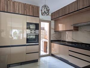 a kitchen with stainless steel appliances and wooden cabinets at Villa golf prestigia marrakech in Marrakech