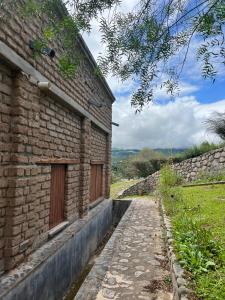 um edifício de tijolos com um passadiço de pedra ao lado em La Ramada em Tafí del Valle