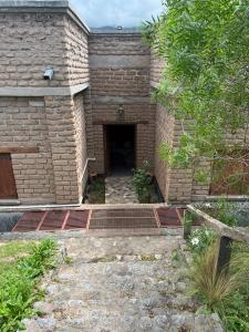 un accès à un bâtiment en briques avec une porte dans l'établissement La Ramada, à Tafí del Valle
