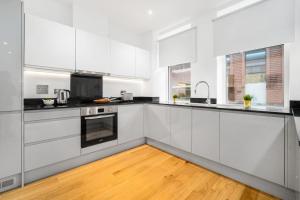a white kitchen with white cabinets and a wooden floor at New 3 Bed Duplex/ City Centre in Birmingham