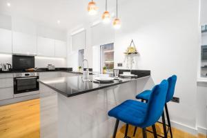 a kitchen with a counter and two blue chairs at New 3 Bed Duplex/ City Centre in Birmingham