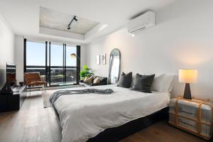 - une chambre avec un grand lit et une grande fenêtre dans l'établissement Modern, Industrial Hideaway, à Melbourne