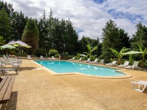 una piscina con sedie e ombrelloni di Maison de charme avec piscine, au cœur de Prats du Périgord, idéale pour 4 pers. et animaux acceptés - FR-1-616-353 a Prats-du-Périgord