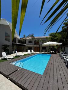 a swimming pool with a wooden deck and chairs at OCEAN DRIVE LODGE in Montañita