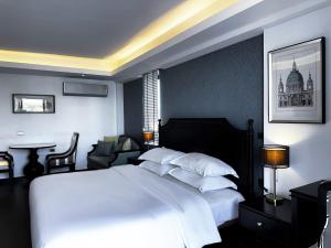 una camera da letto con un grande letto con lenzuola e cuscini bianchi di Glory Boutique Suites 清迈古城荣耀精品酒店 a Chiang Mai