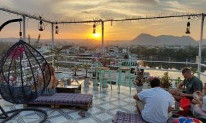 烏代浦的住宿－Raahi Backpacker's Hostel，一群人坐在阳台上欣赏日落