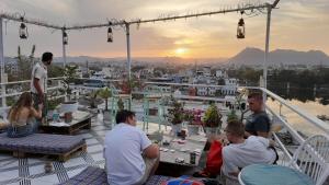 a group of people sitting on a deck watching the sunset at Raahi Backpacker's Hostel in Udaipur