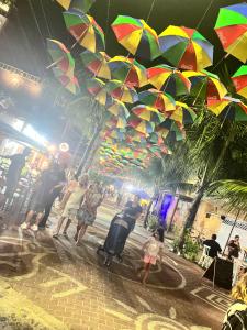 a group of people walking in the rain with umbrellas at Sobrado para até 16 pessoas px ao centro in Porto De Galinhas +32 photos