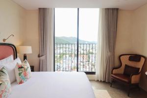 a hotel room with a bed and a large window at L'amor Boutique Hotel Quy Nhơn in Quy Nhon