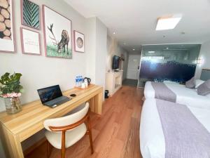 Schlafzimmer mit einem Bett und einem Schreibtisch mit einem Laptop in der Unterkunft Fresh Hours Hotel - West Lake Qingchun in Hangzhou