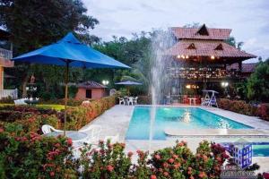 a swimming pool with a fountain in front of a house at Finca Villa Lili in Santa Fe de Antioquia