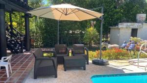 a patio with chairs and an umbrella next to a pool at Finca Villa Lili in Santa Fe de Antioquia