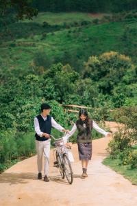 a man and a woman walking a bike on a dirt road at Tám Trình Coffee Farm in Hoat
