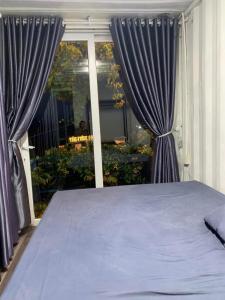 1 dormitorio con 1 cama con cortinas azules y ventana en Tám Trình Coffee Farm, en Hoat