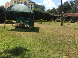 un kiosque avec une table et un banc dans un champ dans l'établissement Stone Cottages, Kilimani, à Nairobi