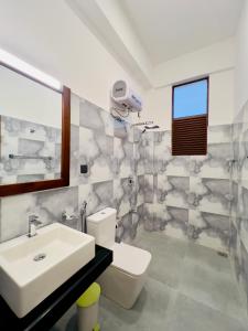 een badkamer met een wastafel, een toilet en een spiegel bij The Golden Park Hotel in Anuradhapura