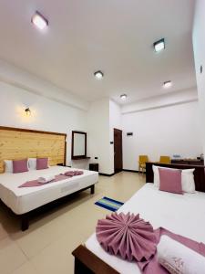 twee bedden in een grote kamer met twee tafels bij The Golden Park Hotel in Anuradhapura