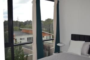 a bedroom with a bed and a large window at ZMITH Apartment - BROOKE Canberra in Belconnen