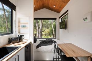 a small kitchen with a table and a bed in a tiny house at Bright Cabin Park in Bright