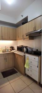 a kitchen with wooden cabinets and a stove top oven at Modern 2BR Condo with Fiber Net in Davao City