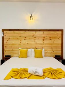 The Golden Park Hotel في أنورادابورا: سرير مع شراشف صفراء وبيضاء ومخدات صفراء