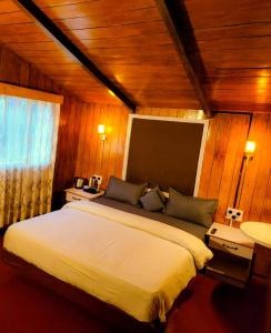 um quarto com uma cama grande num quarto com paredes de madeira em Wood House 1 em Ooty