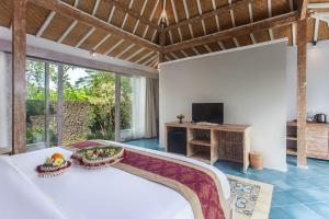 1 dormitorio con 1 cama y TV en una habitación en Tanta Escape by Pramana Villas, en Tegalalang