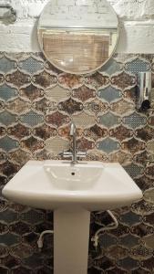 a white sink in a bathroom with a mirror at Shivoham the earthen Home in Dehradun