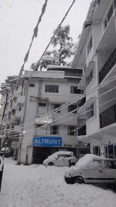 un edificio de apartamentos con coches aparcados en la nieve en Abuzz Oxfordcaps Simla en Shimla