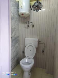 a small bathroom with a toilet and a water tank at Abuzz Oxfordcaps Simla in Shimla